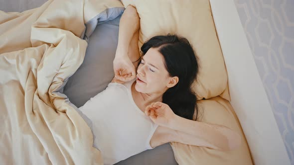 Top View of Young Awakening Lady in Bed and Stretching Tracking Shot Slow Motion