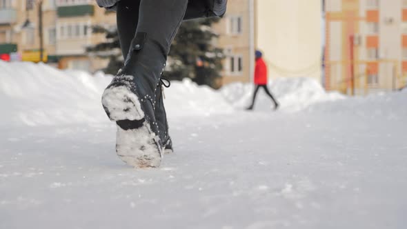 Female Feet in Black Boots Winter Walking in Snow