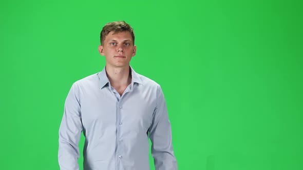 Young Man in a Gray Shirt Going and Looking Forward Against a Green Background. Slow Motion.