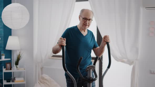 Retired Man Doing Cardio Exercise with Stationary Bicycle