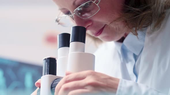 Low Angle Handheld Shot of Mature Female Researcher Looking Through a Microscope