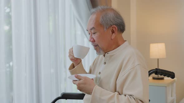 Asian Senior Elderly disabled man drink a cup of coffee with smile face enjoy stay nursing home care