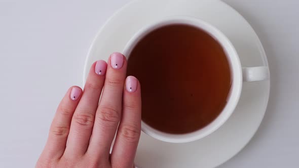 Woman Showing Hands with Beautiful Nude Manicure Holding Tea Cup