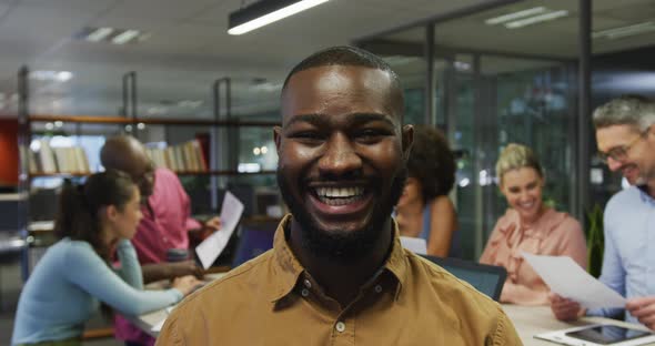 Portrait of african american businessman smiling over diverse business colleagues talking