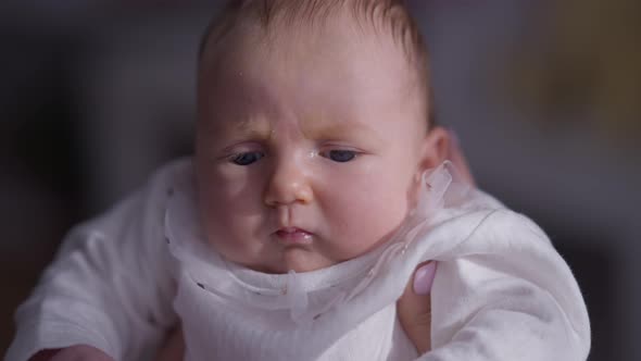 Headshot Newborn Baby Girl with Dissatisfied Facial Expression Indoors at Home