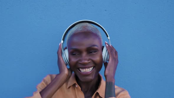 Happy senior Afro woman having fun dancing and listening music with wireless headphones