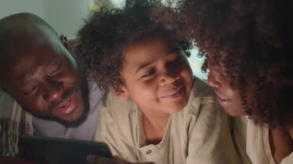 African American Parents and Kid Using Tablet in Evening at Home