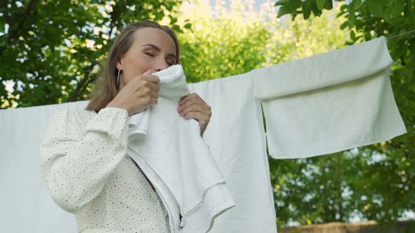 A Young Woman Stands in Front of an Apple Tree a Woman Holds Fresh Underwear in Her Hands Sniffs a