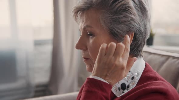 Aged Customer Support Service Worker Putting Stylish Earphone on Ear