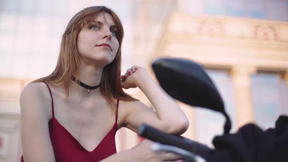 Beautiful Young Redhaired Woman Motorcyclist with Her Motorcycle and Helmet