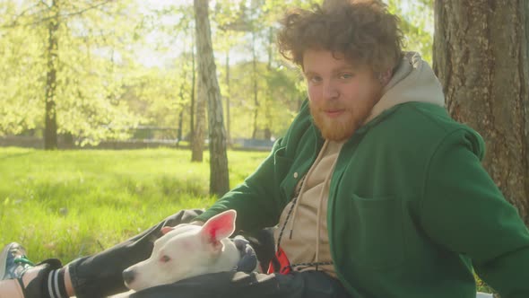 Portrait of Man Resting on Green Lawn with Staffordshire Terrier Dog