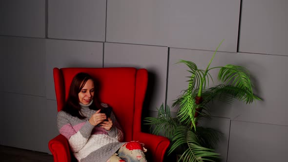 Woman Sitting in Armchair with Smartphone