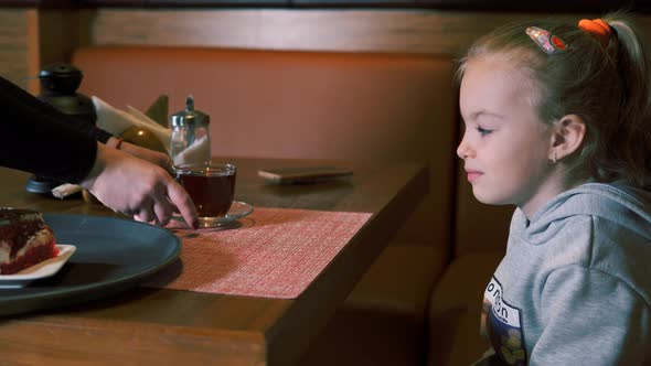 Little Girl is Served Dessert with Fresh Strawberries and Tea on a Tray