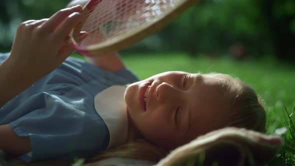 Dreamy Girl Lying on Blanket Touching Racket Strings in Golden Sunlight Closeup