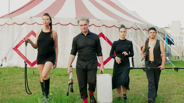 Circus performers carrying fire juggling equipment in front of tent