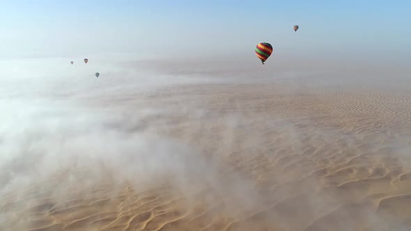 Aerial view of hot-air-balloon flying in the clouds on desert in Dubai, U.A.E.