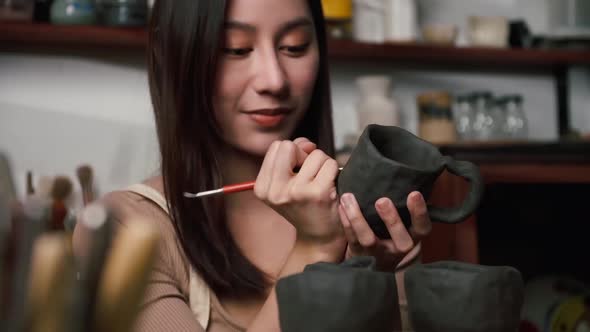 A female ceramicist is creating a new pottery in the workshop. Asian woman is enjoying pottery work.