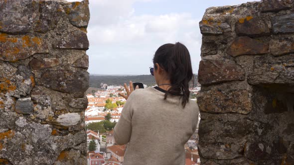 Caucasian woman photographing with cellphone city view of Montemor o Novo from the castle