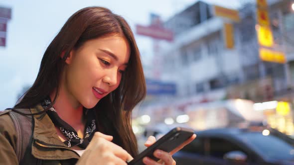 Asian beautiful woman backpacker scrolling on phone while walk in city.