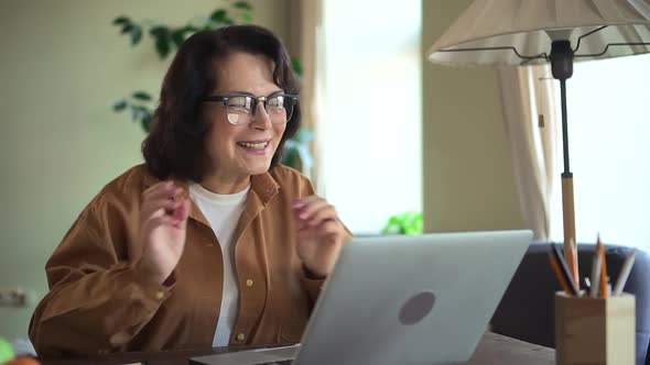 Cheerful Elderly Woman Talk with Friend on Online Video Call at Home