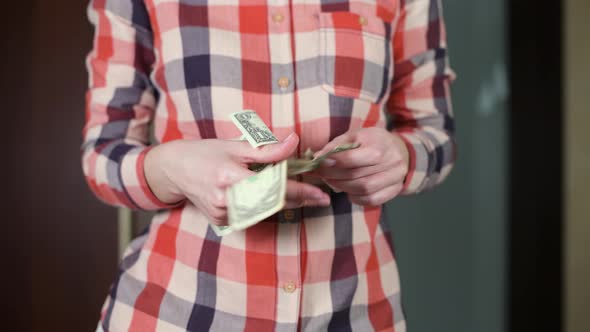 girl straightens wrinkled dollar bills and folds together