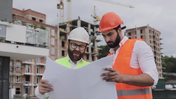 Architect Expert Engineers Talking and Analyze Design Plan Standing Under Construction Site