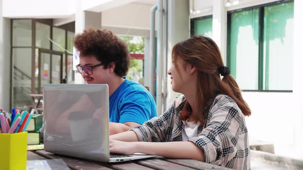 A happy group of attractive young people is tutoring exams with study books, sitting on table alt