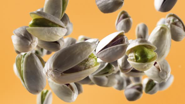 Flying of Pistachios in Pale Orange Background