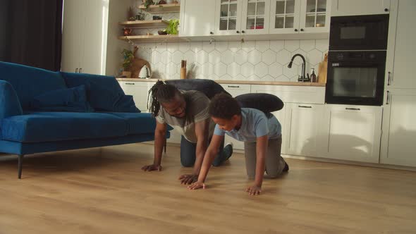 Cheerful School Age Black Boy and Father Playing Funny Game in Domestic Room