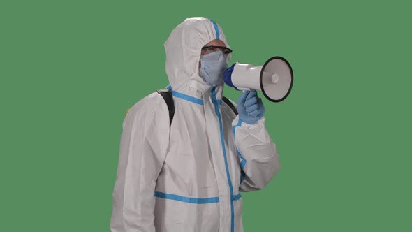 Portrait of a Man in a Protective Suit, Glasses, Gloves and a Medical Mask Speaks Into a Megaphone