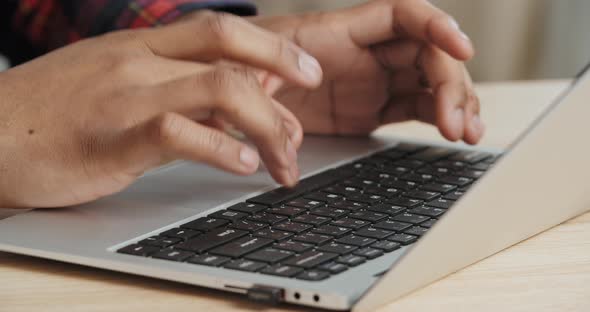 Close Up Male Dark Skined Hands Fingers Typing Email Working with Portable Computer Laptop at Table