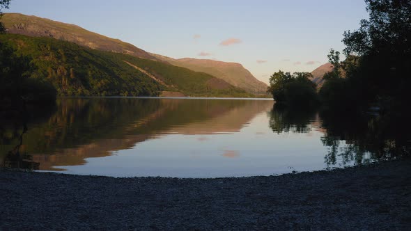 Peaceful little bay on Llyn Padarn Lake during sunset, beautiful reflection on water surface, Snowdo