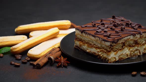 Portion of Traditional Italian Tiramisu dessert, coffee beans and savoiardi cookies