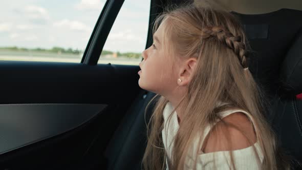 Caucasian girl of 8 years looking out of the car window while car trip.  Shot with RED helium camera