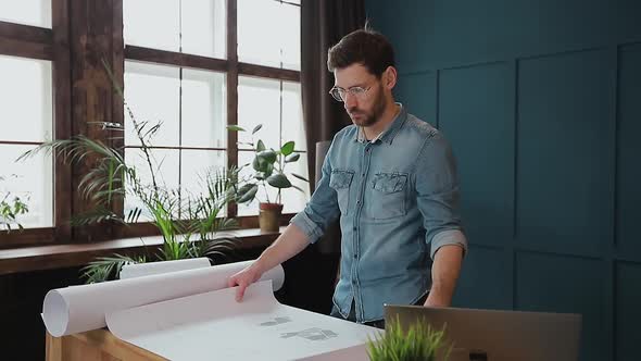 Close Up Shot of Young Man Hands Engineer Opening the Paper and Checking the Construction Drawings