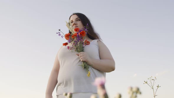 Body Positive Woman with a Bouquet in a Field of Wild Flowers