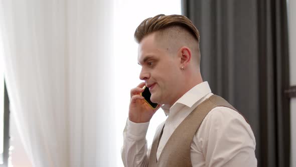 Young Man in Vest From Threepiece Suit Angrily Listens to What They Say to Him on Phone