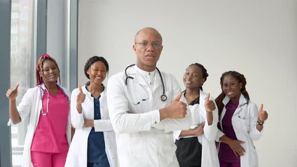 An African American Doctor and Nurse Stand in Front of the Camera and Look Straight Ahead