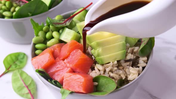 Hawaiian poke - brown rice, salmon, edamame, cucumber and avocado in gray bowl.