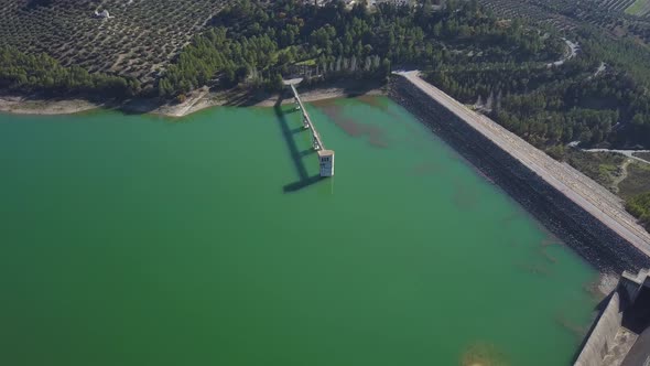 Aerial view of a big reservoir with a control tower and a bridge in the south of Spain.