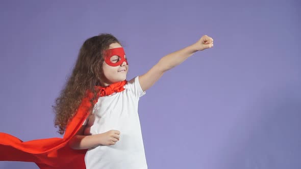 Cheerful Little Girl Wearing Red Mask and Cloak Isolated Purple Background