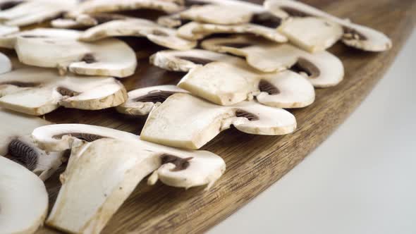 Sliced fresh champignon mushrooms on a cutting wooden board