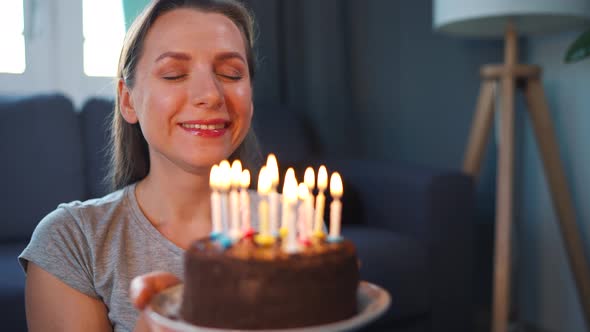 Happy Excited Woman Making Cherished Wish and Blowing Candles on Holiday Cake Celebrating Birthday