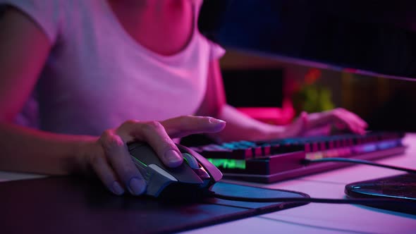 Woman Gamer Hands Using Wired Computer Mouse and Typing on Neon Keyboard Playing Video Games at