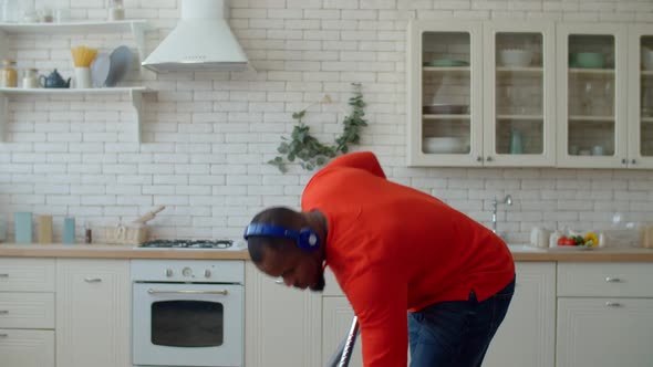 Portrait of Black Man in Headphones Vacuuming During Cleanup