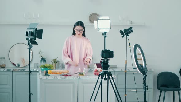 Young Cheerful Woman is Cutting Food While Filming in a Vlog