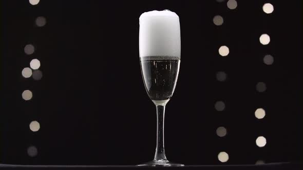 Half Empty Glass of Champagne Filled To the Brim, Bokeh Blinking Black Background