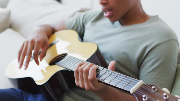 Happy african american man plays guitar and singing at home