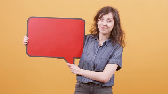 Young Girl Over Yellow Background Holding a Red Speech Balloon