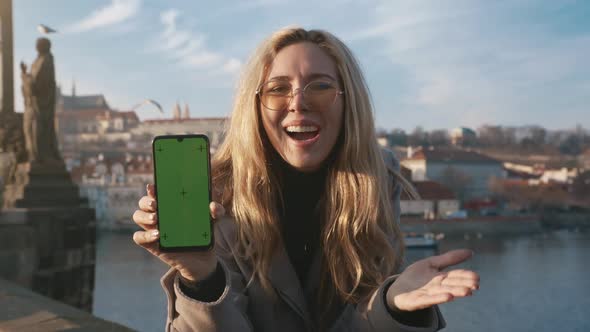 Beautiful Girl Holding a Smartphone in the Hands of a Green Screen